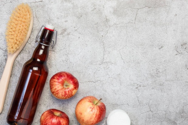 Eine Flasche Essig neben Äpfeln und einer Bürste | Credit: iStock.com/Svetlana Evgrafova