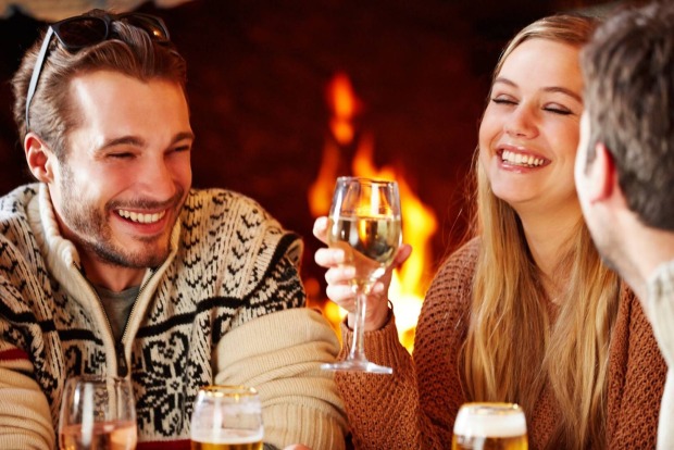 Gesellige Runde junger Frauen und Männer vor dem Kamin | Credit: iStock.com/Chris Cross