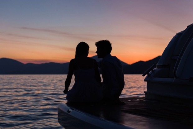 Junges verliebtes Paar im Sonnenuntergang am Ufer eines Sees | Credit: iStock.com/Dreamer Company