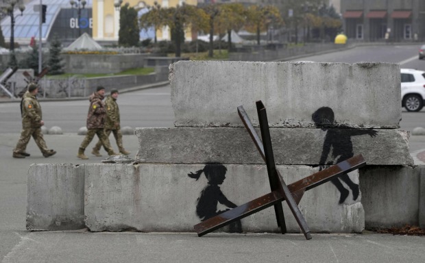 Werk von Banksy: Zwei Kinder, die eine Panzerfalle aus Metall als Wippe nutzen