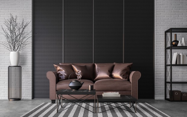 Eine braune Couch steht vor einer schwarzen Wand | Credit: iStock.com/runna10