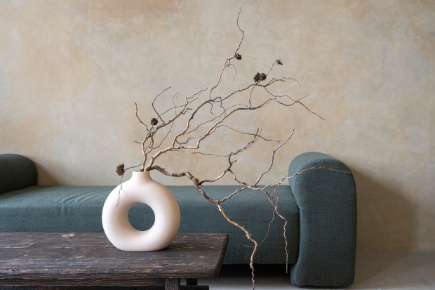Vase mit getrockneten Ästen steht auf einem kleinen Holztisch | Credit: iStock.com/brizmaker