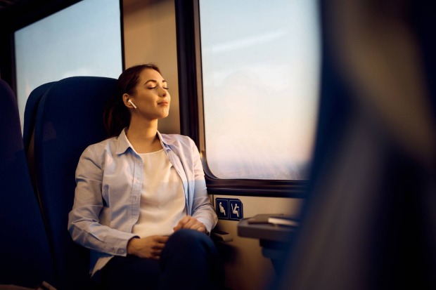 Frau genießt die Zugfahrt mit geschlossenen Augen beim Musikhören | Credit: iStock.com/Drazen Zigic