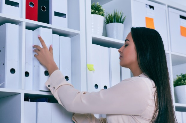 Frau legt ihre Dokumente in Ordner ab | Credit: iStock.com/Cameravit