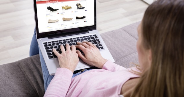 Frau tippt in Laptop mit Onlineshop am Display