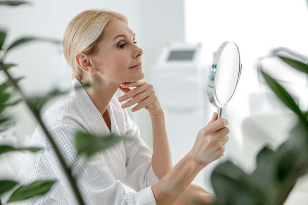 Frau kontrolliert ihre Haut im Spiegel | Credit: iStock.com/YakobchukOlena