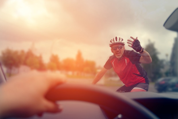 Ein wütender Fahrradfahrer ärgert sich über einen Autofahrer.
