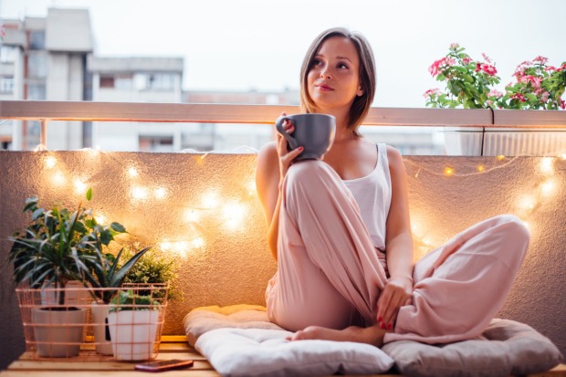 Frau sitzt auf einem Kissen am Balkon | Credit: iStock.com/petrunjela