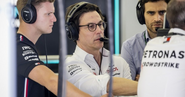 Toto Wolff während mit Kopfhörern und Brille deutet auf einen Bildschirm. Neben ihm Rennfahrer Mick Schumacher