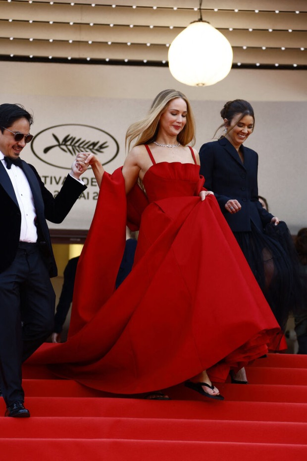 Jennifer Lawrence in einem roten Kleid mit schwarzen Flip-Flops.
