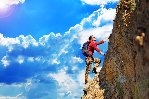 Mann klettert an einer Wand hoch | Credit: iStock.com/vetkit