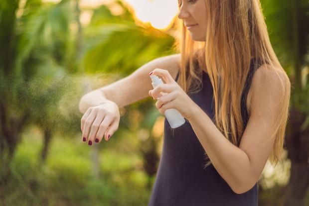 Junge Frau sprüht sich mit Insektenschutz ein | Credit: iStock.com/galitskaya