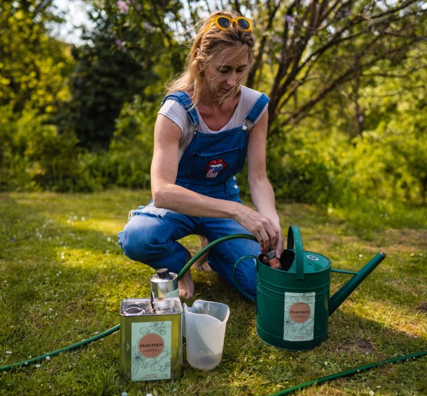 Frau füllt Giekanne im Garten mit Wasser und Dünger | Credit: Planteen