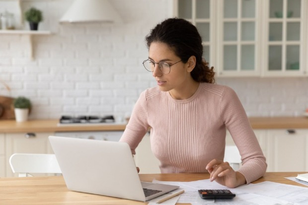 Frau berechnet Kosten für Hauskauf | Credit: iStock.com/fizkes