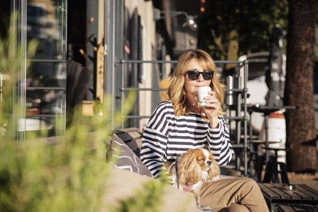 Frau sitzt mit Hund in der Stadt | Credit: iStock.com/Szepy