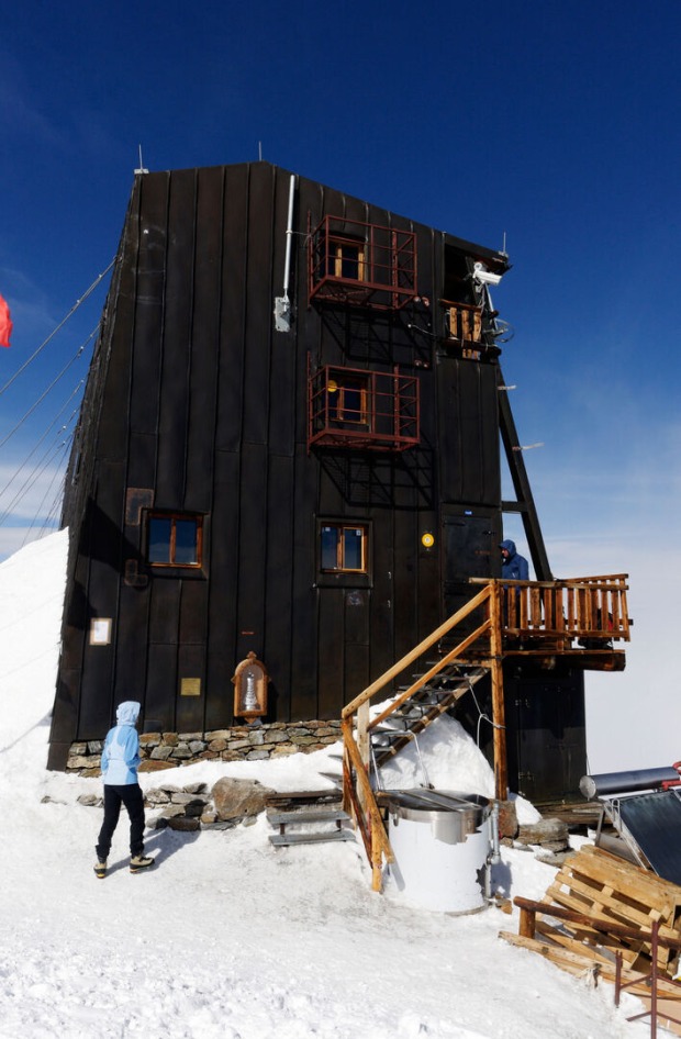 Schmale Seite einer dunkelbraunen Hütte im Schnee
