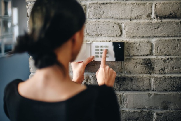 Frau stellt Alarmanlage ein | Credit: iStock.com/djedzura