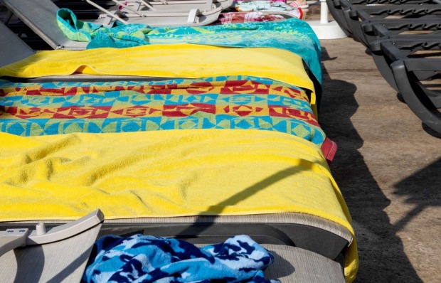Mit Handtüchern reservierte Liegen am Pool.
