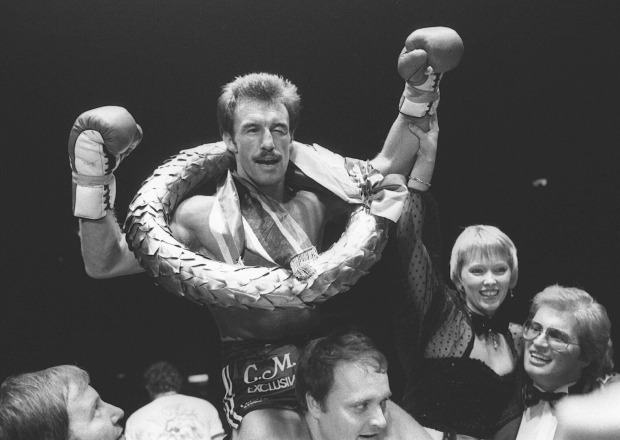 Schwarzweiß-Aufnahme des Boxers René Weller, der auf den Schultern eines seiner Teammitglieder durch den Ring getragen wird und einen Siegerkranz um den Hals trägt