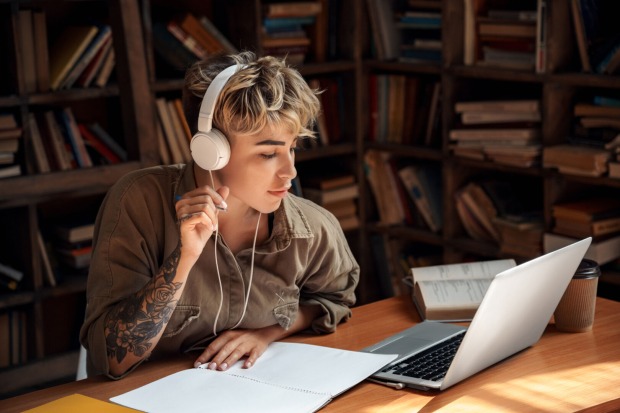 Schülerin sitzt mit Kopfhörern vorm Laptop.