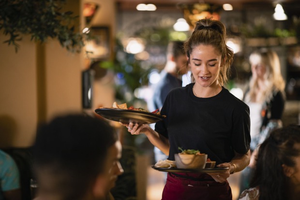 Junge Frau bringt Teller zum Gast in einem Restaurant