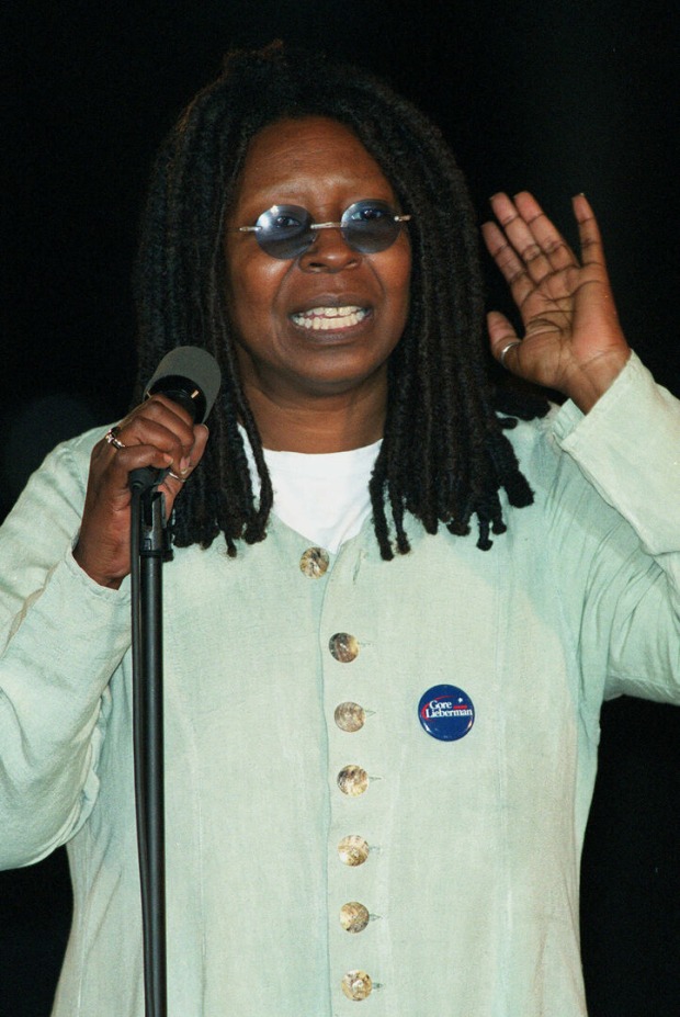 Whoopi Goldberg mit Mikrofon in der Hand und Sonnenbrille.