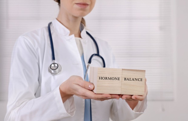 Ärztin hält Holzwürfel mit Aufschrift "HORMONE BALANCE" in den Händen