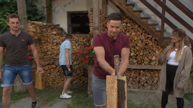 Kandidat Stefan hackt Holz. Dabei trägt er ein weinrotes T-Shirt.