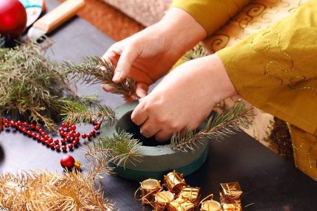 Eine Frau bindet einen Adventkranz selbst.