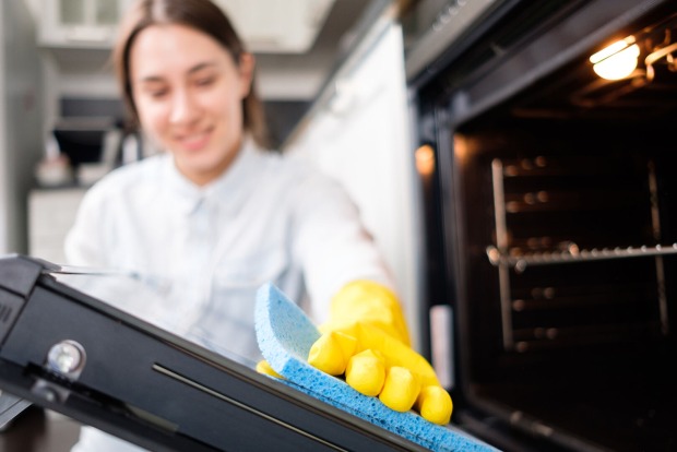 Frau reinigt Backofen | Credit: iStock.com/Alexander Medvedev
