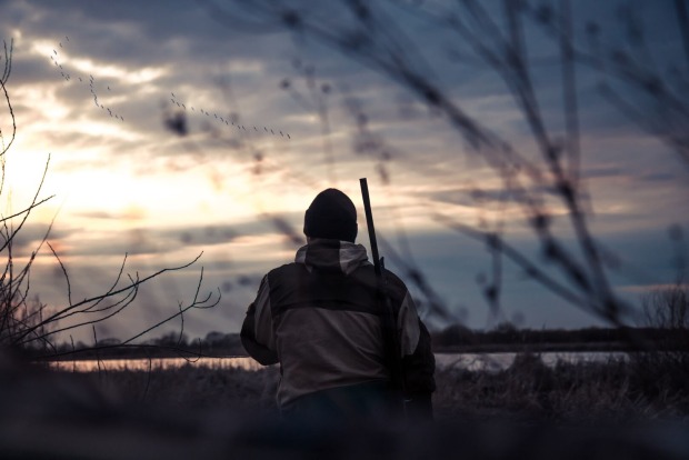 Ein Jäger in der Abenddämmerung von hinten.