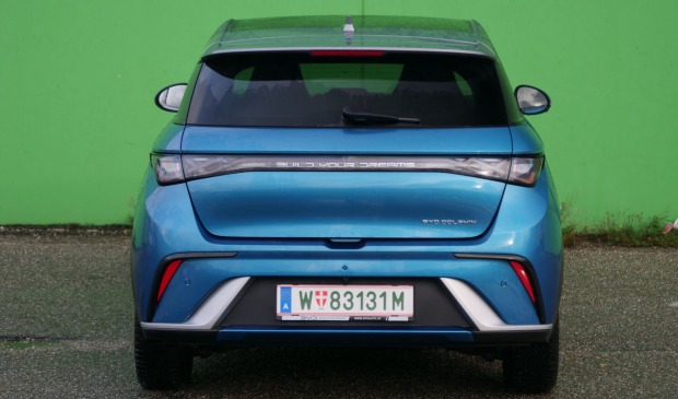 Heckansicht des BYD Dolphin vor einer grünen Wand