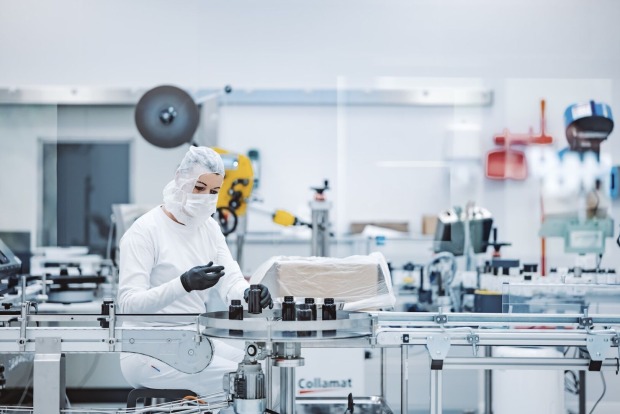 Produktionsmitarbeiterin füllt Kapseln ab.
