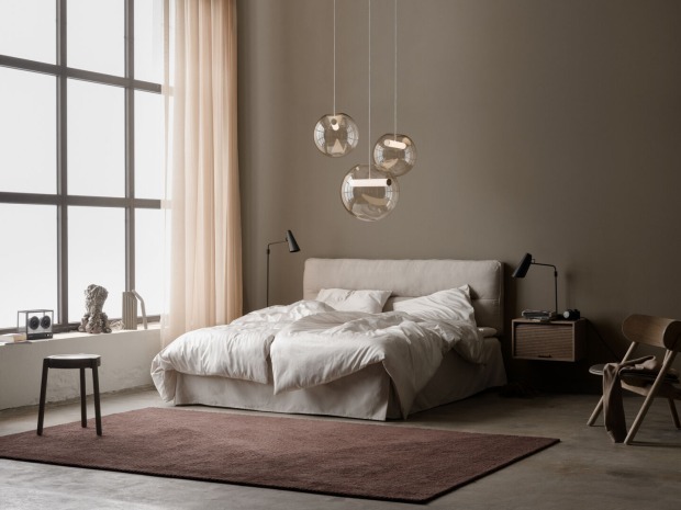 Doppelbett in hohem Raum mit drei zarten Lichtkugeln