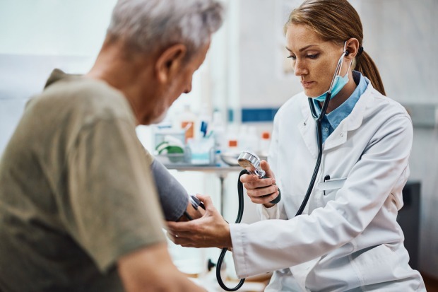 Eine Ärztin misst in ihrer Praxis den Blutdruck eines älteren Patienten