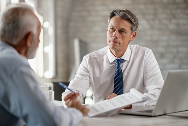Klient mit Notar bei der Testament-Unterzeichnung | Credit: iStock.com/Drazen Zigic