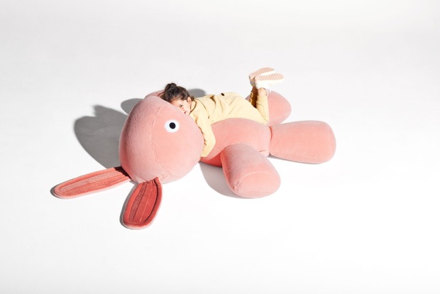 Riesiges Kuschelkaninchen, auf dem ein Kind liegt