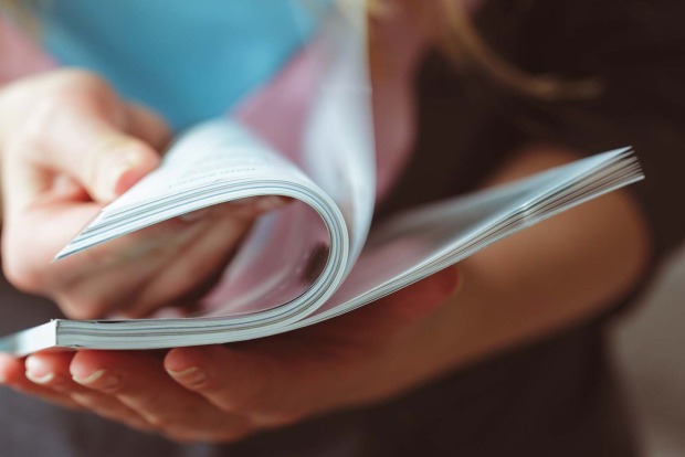 Frau blättert in Zeitschrift | Credit: iStock.com/FabrikaCr