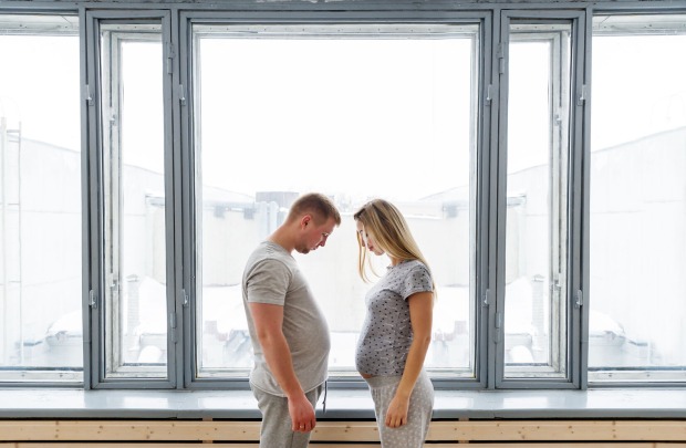 Mann und Frau mit Schwangerschaftsbauch sehen sich an