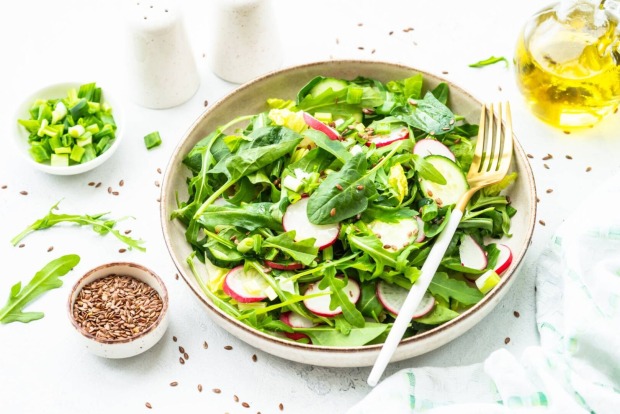 Schale mit grünen Salatblättern und frischen Radieschen