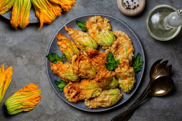 Teller mit goldbraun gebackenen Zucchiniblüten