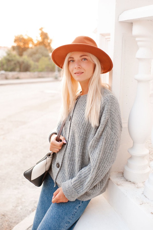 Frau trägt Strickjacke und Hut | Credit: iStock.com/morrowlight