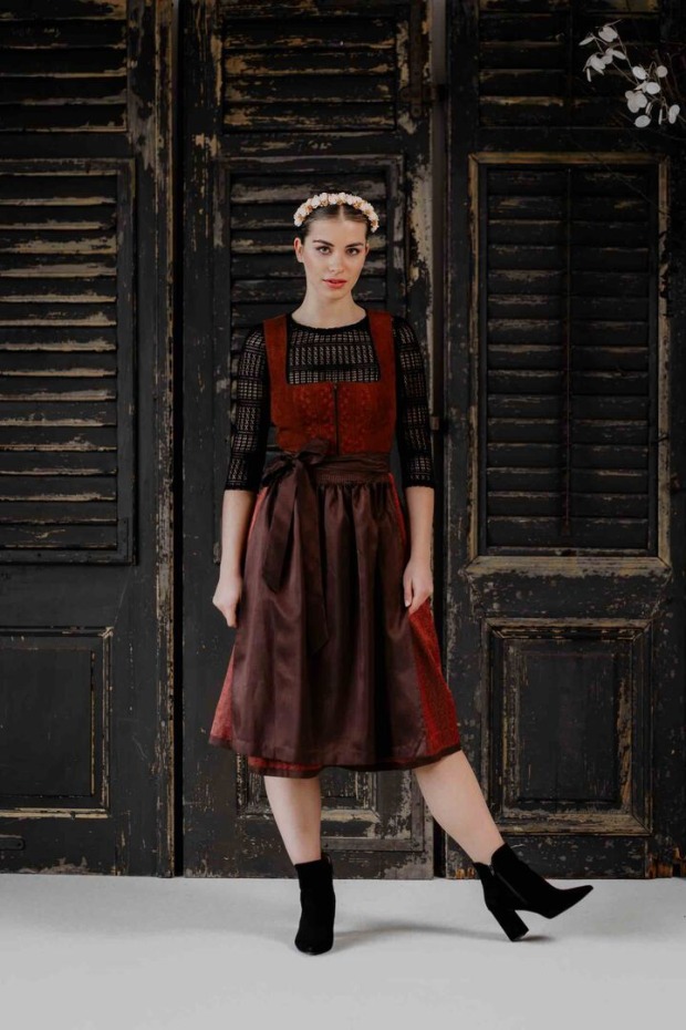 Model in brombeerfarbigem Dirndl mit schwarzer Bluse