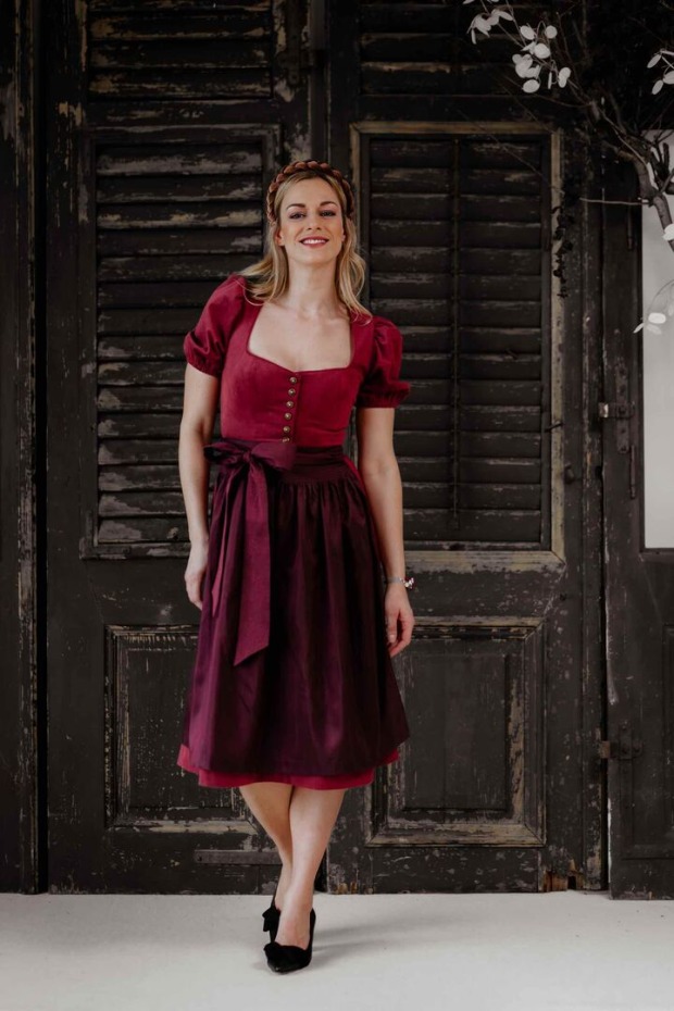 Model trägt brombeerfärbiges Dirndl mit Puffärmeln