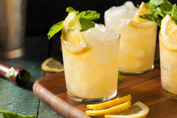 Glas mit gecrushtem Eis, Gin und gelben Sirup, garniert mit einer Zitronenscheibe und frischen Minzblättern