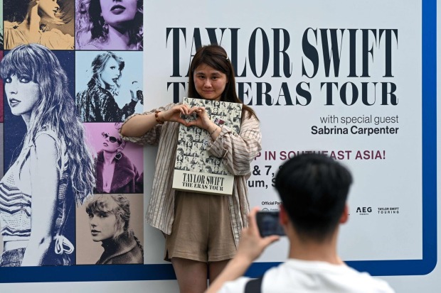 Ein Fan von Taylor Swift posiert vor einem Plakat der Sängerin.