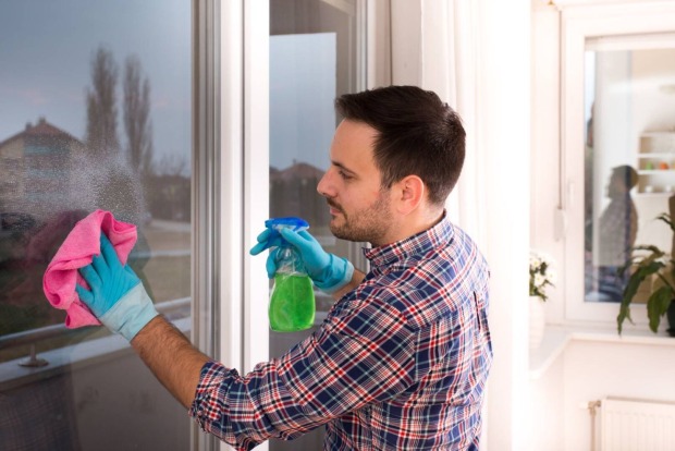 Mann, der gerade hohe Fenster von außen putzt