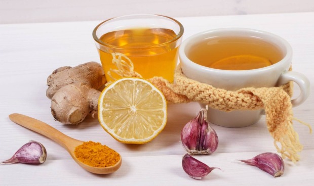 Glas mit heißem Getränk, garniert mit frischem Knoblauch und Zitrone.