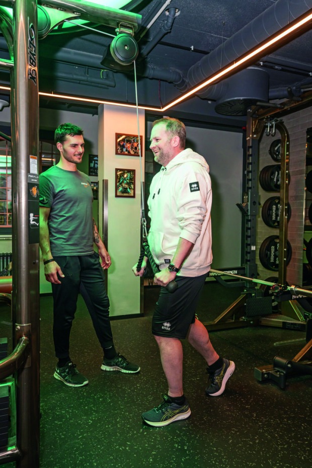 Mann trainiert gemeinsam mit einem Trainer im Fitnessstudio