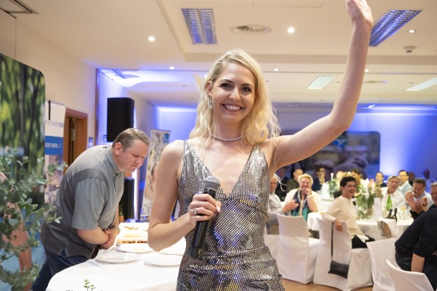 Blonde Frau winkt in die Kamera